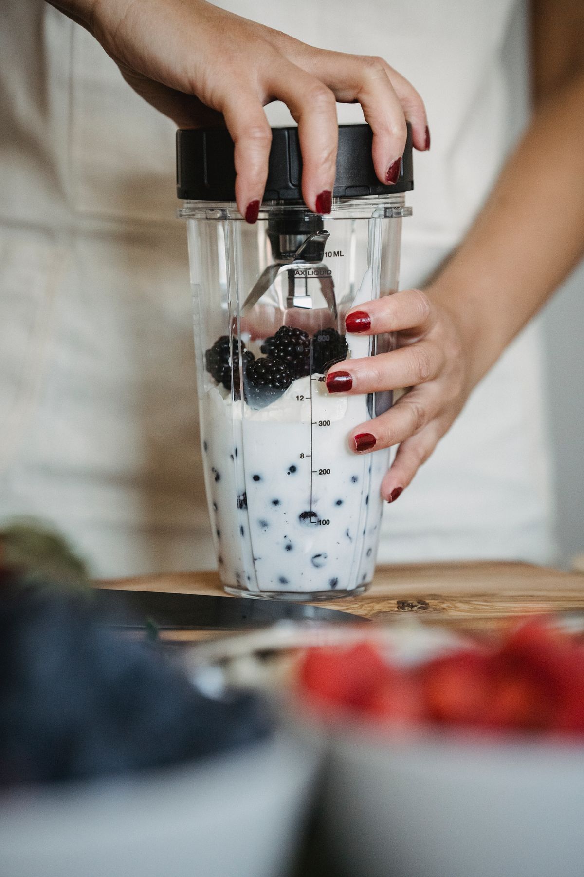 A personal blender cup being filled with berries