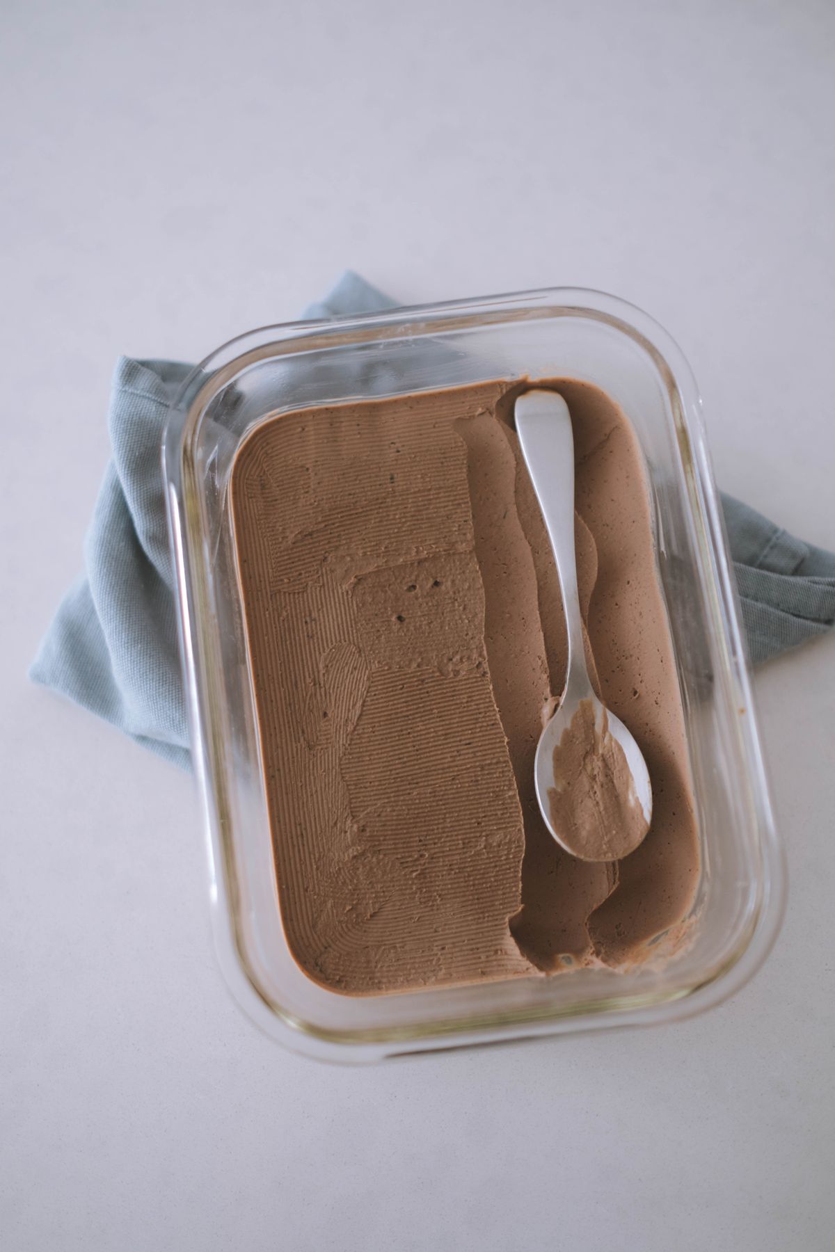 Chocolate ice cream in a glass container with a spoon