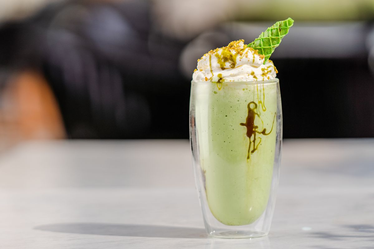 Pistachio milkshake with cream and mint garnish
